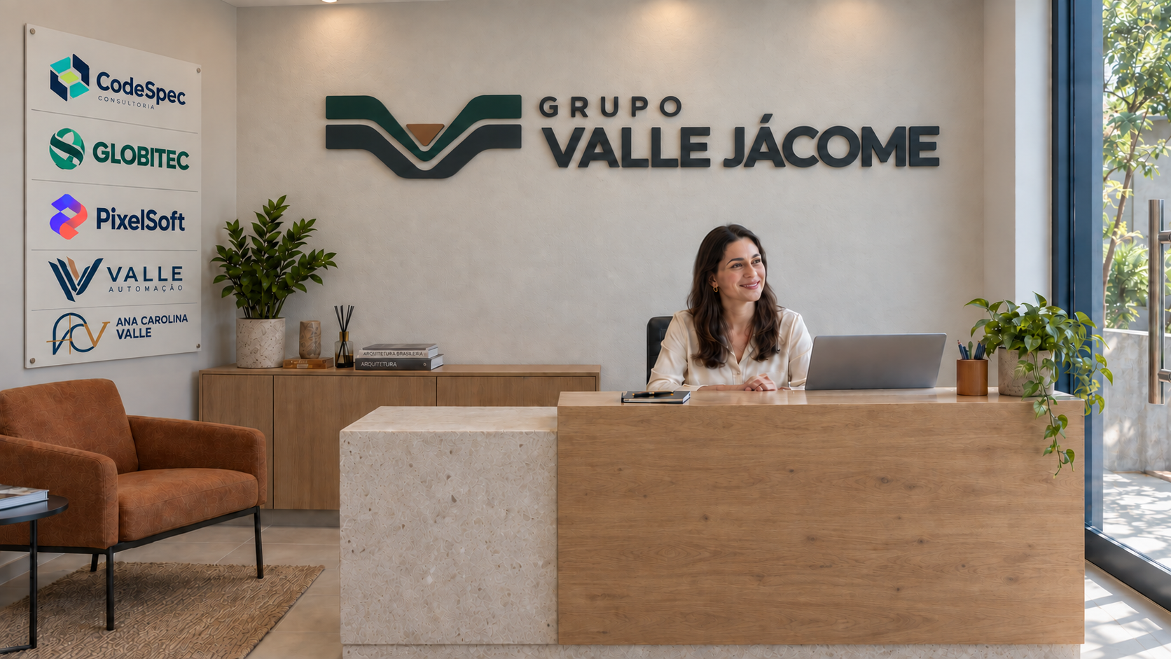 Recepção com balcão de madeira, painel das empresas e letreiro do Grupo Valle Jácome